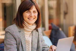 A person wearing a plaid blazer over a white knitted turtleneck sweater representing business insurance coverage.