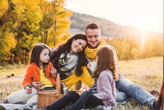 A family of four sitting on a blanket in a grassy field representing life insurance coverage.