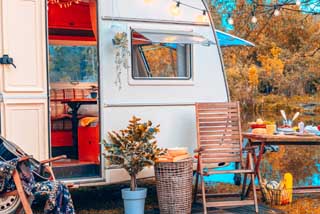 A cozy outdoor scene featuring a white camper trailer with its door open representing recreational vehicle insurance coverage.